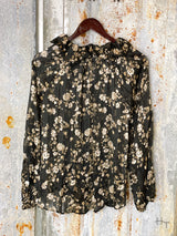 Photo of back of black and gold floral long sleeve top on a hanger with tin background