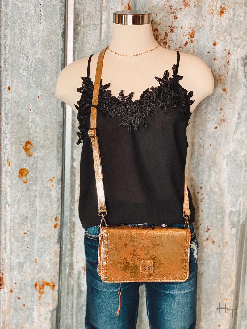 Photo of black cami with floral lace trim on mannequin with metallic gold crossbody purse with tin background