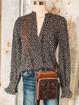 Photo of mannequin with black leopard top with brown leather purse with tooled leather panel on front of crossbody strap
