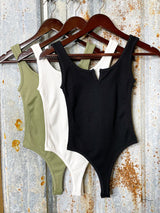 photo of green, white and black body suits hanging on coat hangers