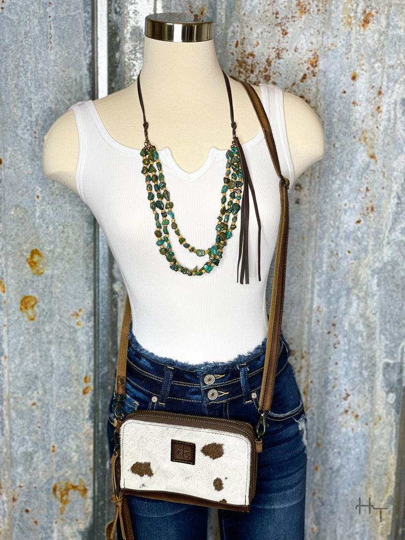 Photo of white bodysuit on mannequin with denim jeans on.  Accessorized with turquoise necklace and cowhide purse.
