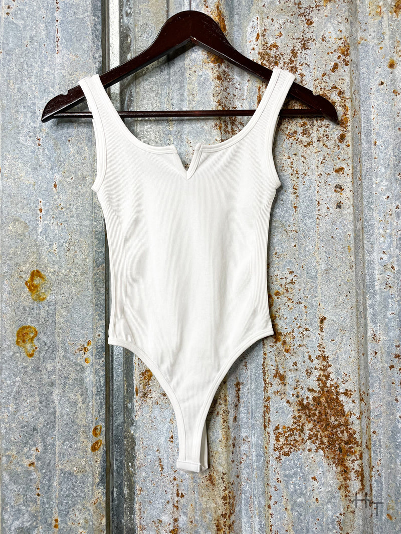 Photo of front view of white bodysuit on clothes hanger