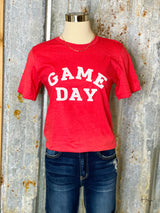 Photo of red tee shirt with words Game Day printed in white on front on a mannequin with a tin background