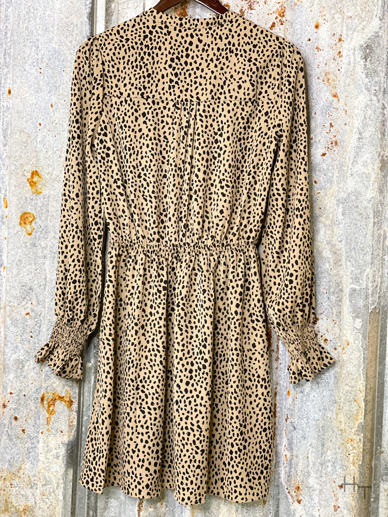 Photo of back view of long sleeve latte brown dress with black spots on a hanger with tin background