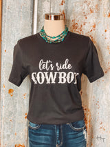 Photo of black tee shirt with Let's Ride Cowboy on front in white paired with turquoise necklace on a mannequin with tin background