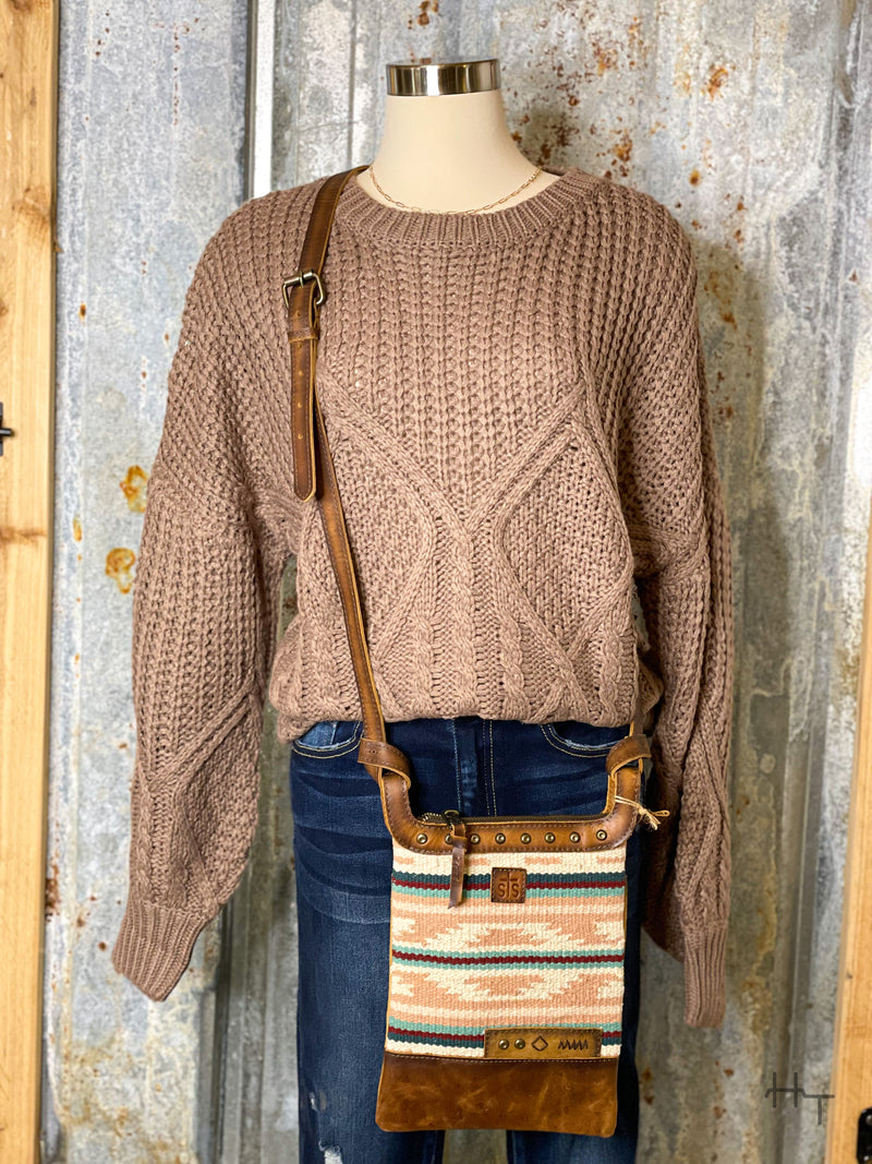Photo of mocha brown knit sweater styled with leather and aztec print crossbody purse on a mannequin with tin background