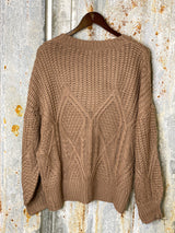 Photo of back view of mocha brown knit sweater on a hanger with tin background