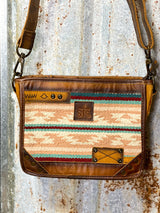 Photo of close up of front of leather purse with pastel aztec print with sts leather patch on front and long crossbody strap