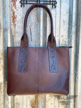 picture of back of westward tote that is dark brown leather with floral tooled leather accents and rolled leather shoulder straps