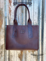 picture of dark brown leather purse with floral tooled leather design accents and rolled leather shoulder straps and leather STS patch