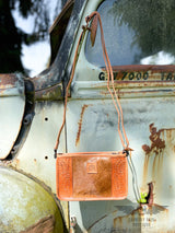 Image of Yipee kiyay claire crossbody purse with crossbody strap.  The purse has a brown cowhide panel in the middle with floral tooled veggie tan leather on each side and a leather patch in the middle with the STS brand.