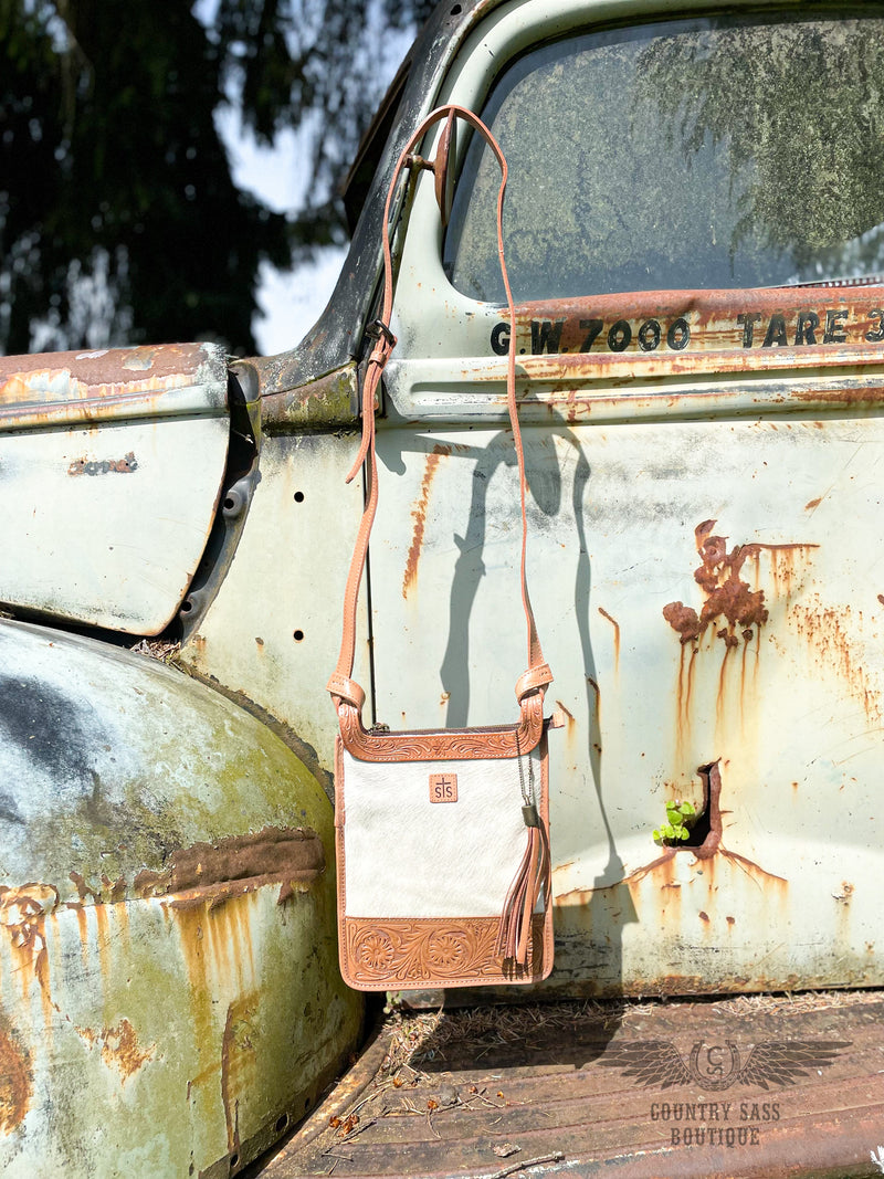 Image of yipee kiyay crossbody purse.  White cowhide front with tooled leather detail on top and bottom with long adjustable crossbody strap.